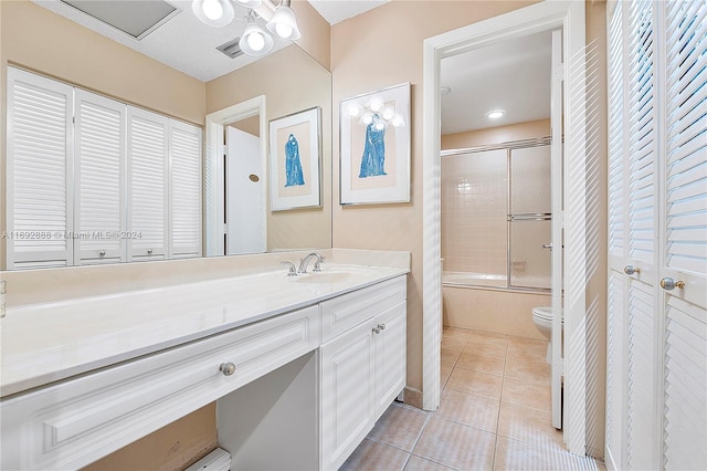 full bathroom featuring shower / bath combination with glass door, tile patterned flooring, vanity, and toilet