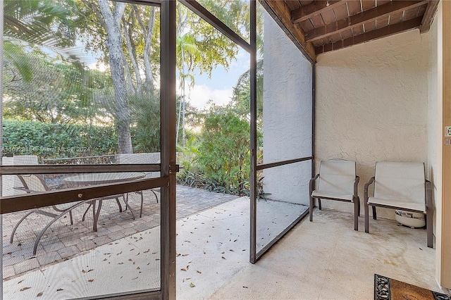 unfurnished sunroom with beam ceiling and a healthy amount of sunlight