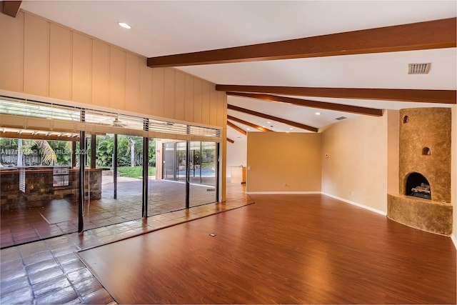 unfurnished living room featuring vaulted ceiling with beams, hardwood / wood-style flooring, and a large fireplace