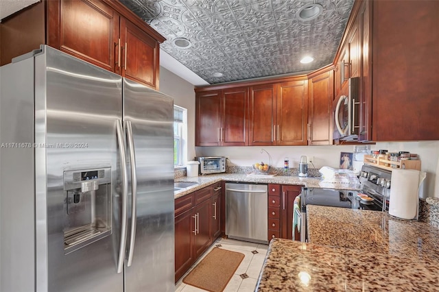 kitchen with appliances with stainless steel finishes, light tile patterned floors, and light stone counters