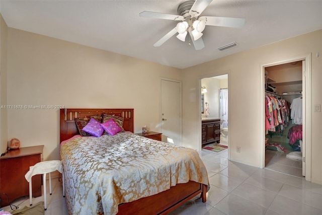 bedroom with ensuite bathroom, a walk in closet, ceiling fan, light tile patterned floors, and a closet