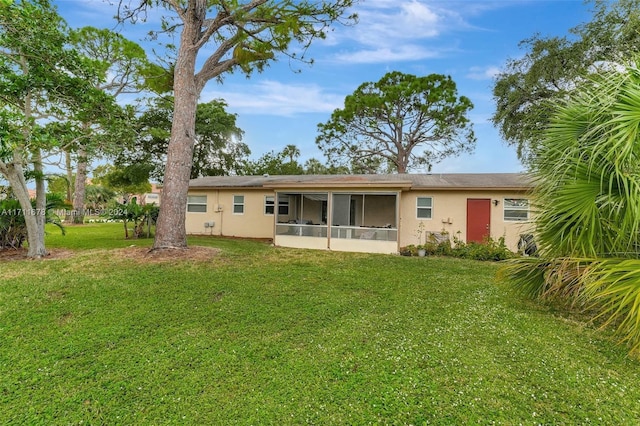 back of house featuring a lawn and a sunroom