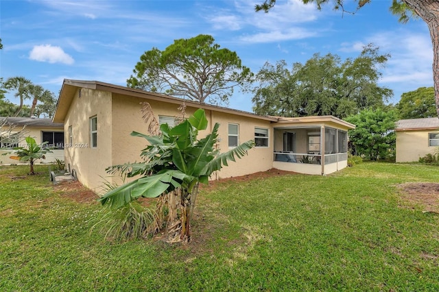 rear view of house featuring a sunroom and a yard