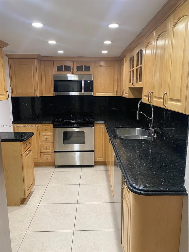 kitchen featuring dark stone countertops, light tile patterned floors, sink, and appliances with stainless steel finishes