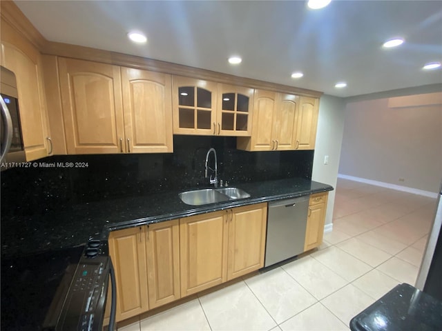 kitchen featuring sink, stainless steel dishwasher, backsplash, dark stone countertops, and light tile patterned floors