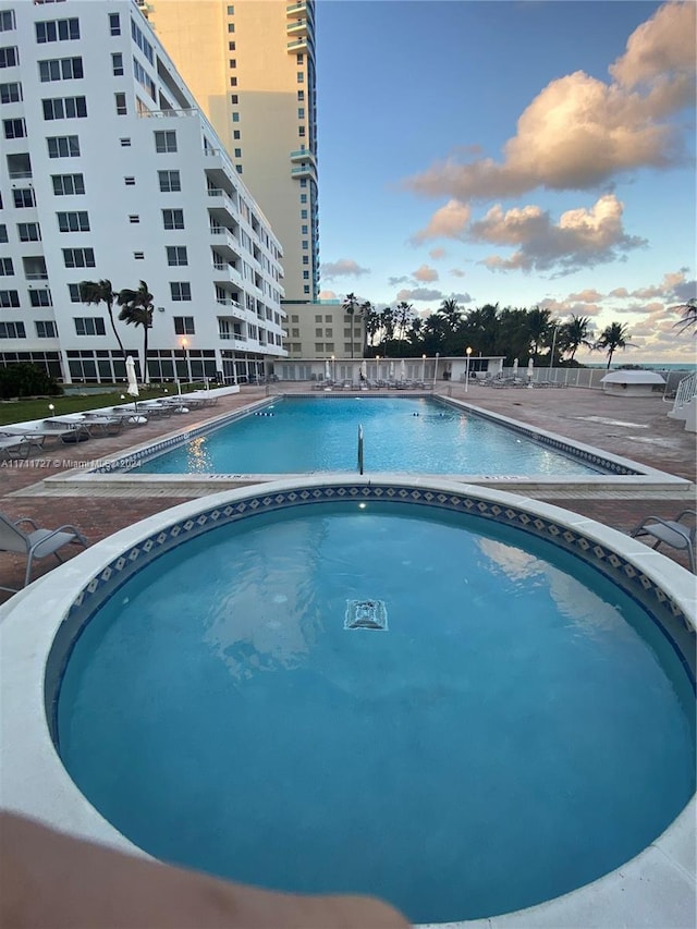 pool at dusk with a community hot tub