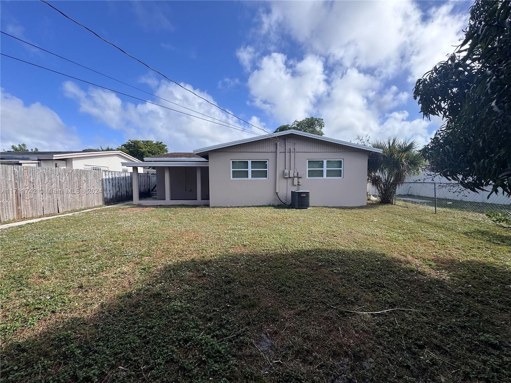 rear view of house with a yard and central AC unit