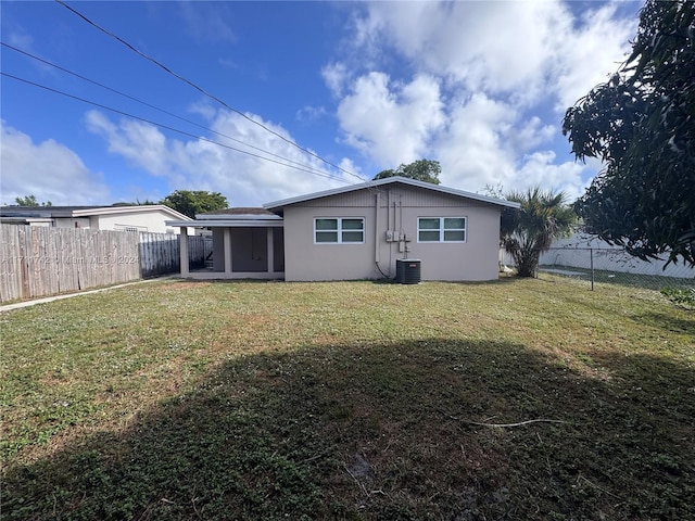 rear view of house with a yard and central AC unit