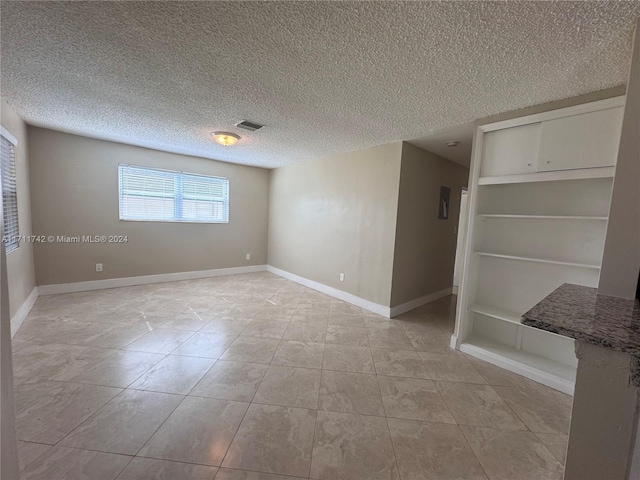 unfurnished room featuring light tile patterned floors and a textured ceiling