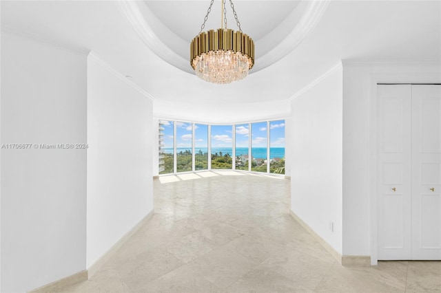 hallway with a tray ceiling, crown molding, expansive windows, and a chandelier