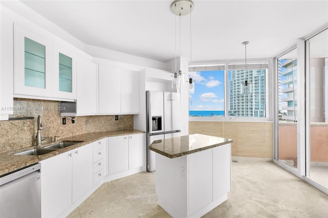 kitchen with sink, stainless steel appliances, dark stone countertops, pendant lighting, and white cabinets