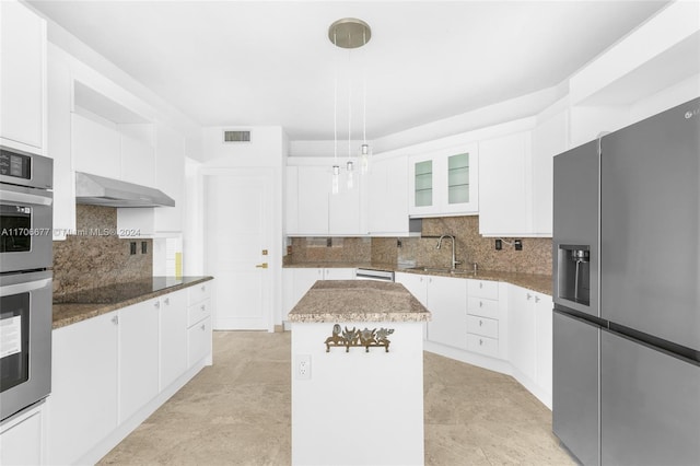 kitchen featuring a center island, ventilation hood, dark stone countertops, appliances with stainless steel finishes, and white cabinetry