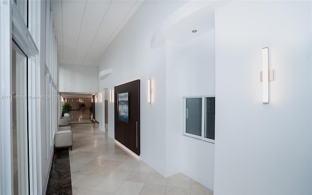 hallway featuring a towering ceiling and light tile patterned flooring