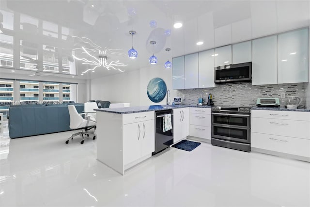 kitchen featuring white cabinets, decorative backsplash, stainless steel appliances, and hanging light fixtures