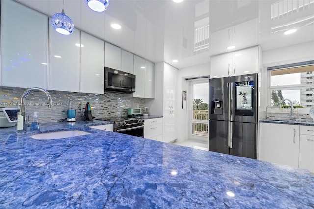 kitchen featuring pendant lighting, sink, decorative backsplash, white cabinetry, and stainless steel appliances