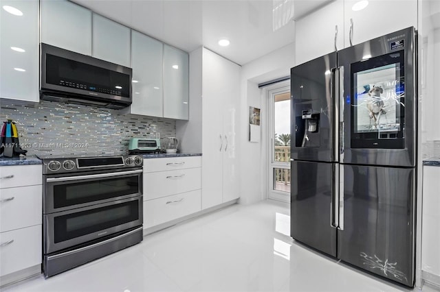 kitchen with backsplash, dark stone counters, white cabinets, light tile patterned flooring, and stainless steel appliances