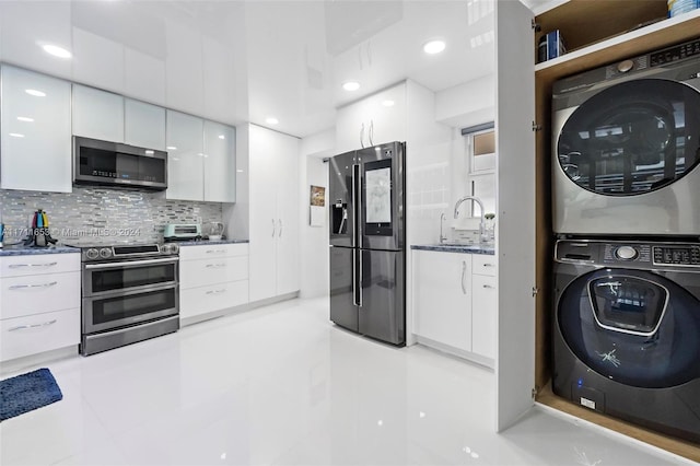 kitchen with sink, tasteful backsplash, white cabinets, stacked washer and clothes dryer, and appliances with stainless steel finishes