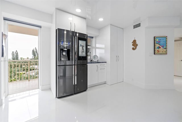 kitchen featuring refrigerator with ice dispenser, white cabinetry, and a wealth of natural light