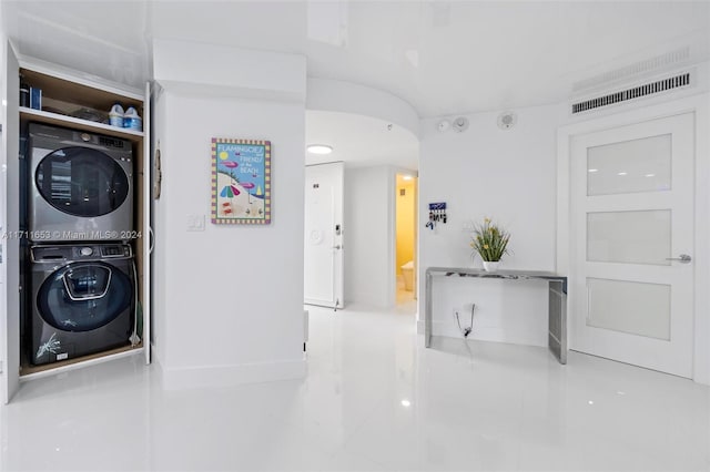 clothes washing area with tile patterned floors and stacked washer and dryer