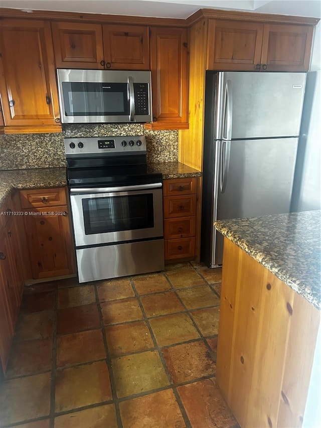 kitchen featuring backsplash, stainless steel appliances, and dark stone counters