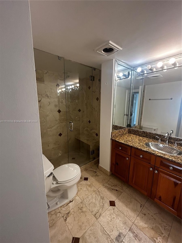 bathroom with vanity, toilet, and a shower with shower door