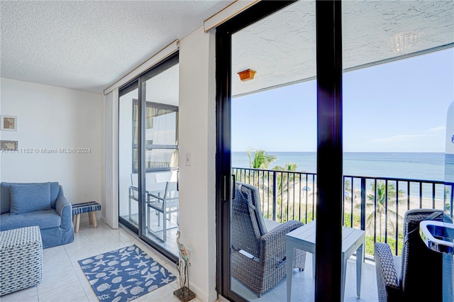 interior space with light tile patterned floors, a textured ceiling, a water view, and floor to ceiling windows