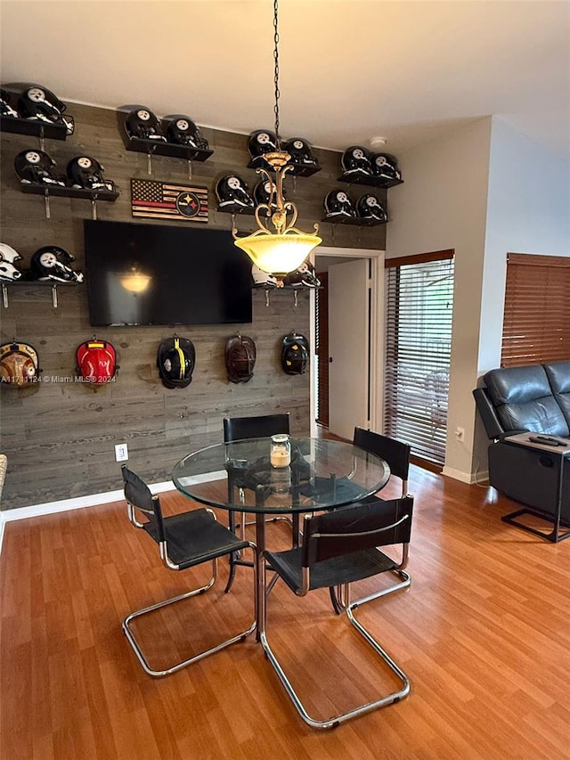 dining area with wooden walls and hardwood / wood-style flooring