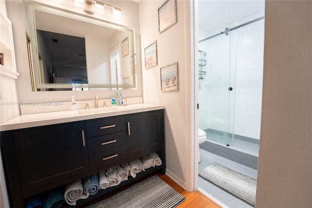 bathroom featuring wood-type flooring, vanity, toilet, and walk in shower