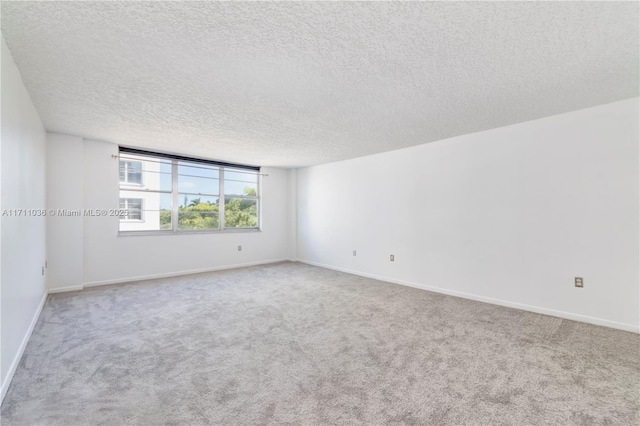 carpeted empty room with baseboards and a textured ceiling