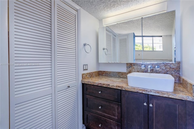 bathroom featuring a textured ceiling, a closet, and vanity