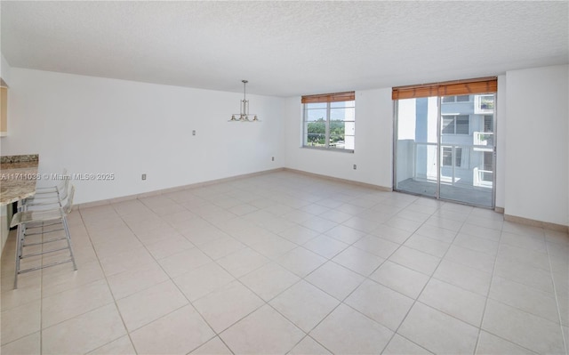 unfurnished living room with a chandelier, a textured ceiling, and baseboards