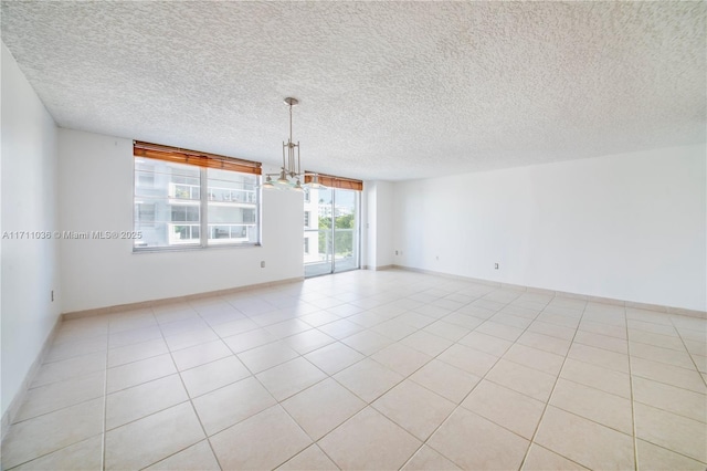 empty room featuring baseboards, a notable chandelier, a textured ceiling, and light tile patterned floors