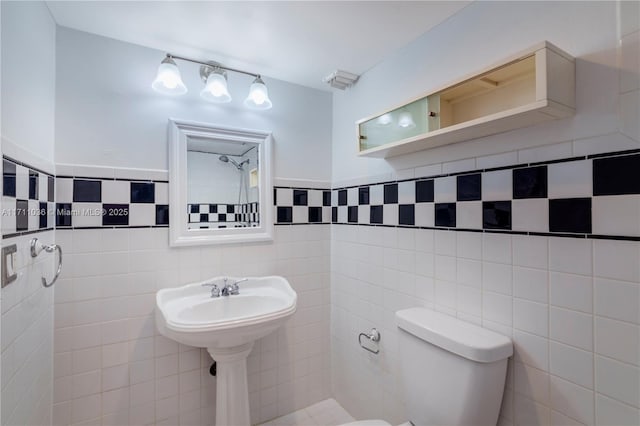 bathroom with toilet, a wainscoted wall, and tile walls