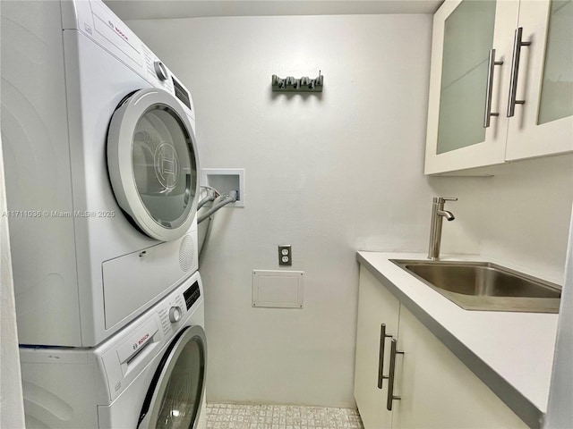 laundry area with a sink, stacked washing maching and dryer, and cabinet space