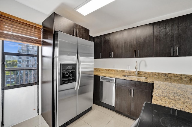 kitchen featuring dark brown cabinetry, sink, light tile patterned flooring, and stainless steel appliances