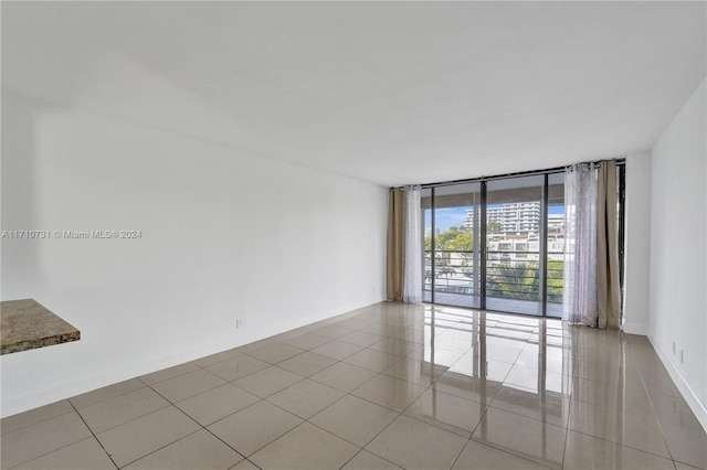 empty room with light tile patterned floors and a wall of windows