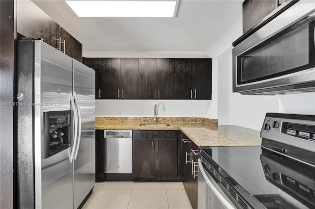 kitchen with dark brown cabinetry, sink, light tile patterned floors, and appliances with stainless steel finishes