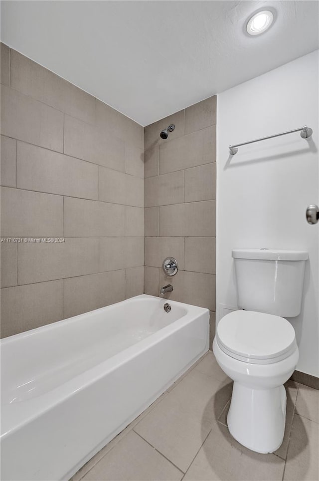 bathroom with tile patterned flooring, tiled shower / bath combo, and toilet