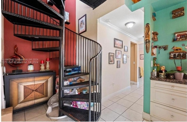 stairway with tile patterned floors and ornamental molding