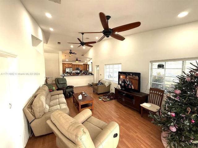 living room with high vaulted ceiling, ceiling fan, light wood-type flooring, and a wealth of natural light