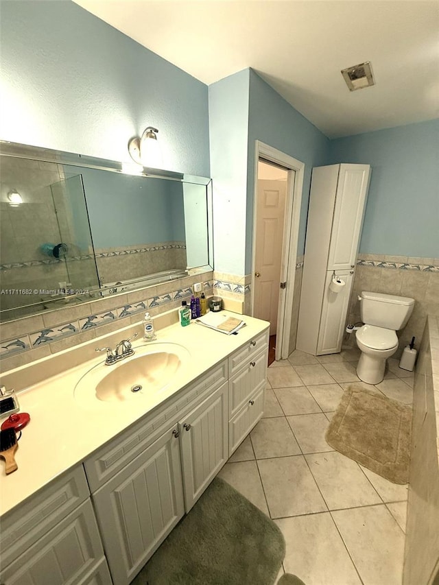 bathroom featuring tile patterned floors, vanity, tile walls, and toilet