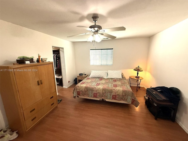 bedroom featuring ceiling fan, dark hardwood / wood-style flooring, a spacious closet, and a closet