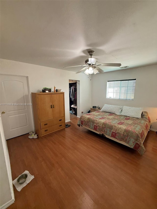 bedroom with hardwood / wood-style floors, a walk in closet, a closet, and ceiling fan