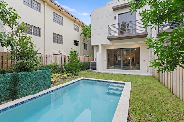 view of pool with a lawn and cooling unit