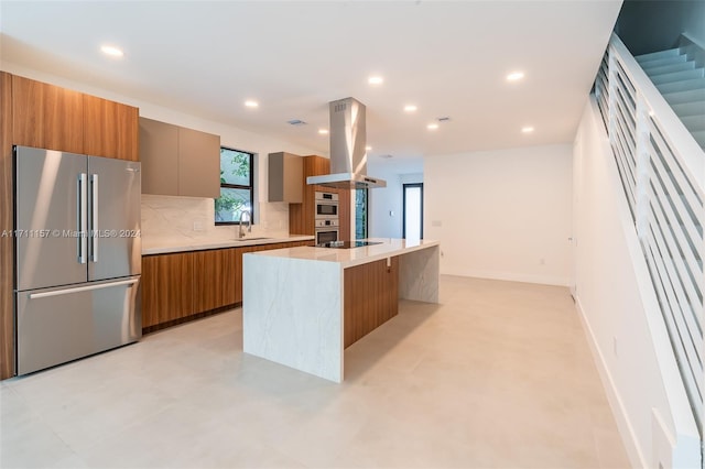 kitchen featuring a center island, sink, a breakfast bar area, high quality fridge, and island range hood