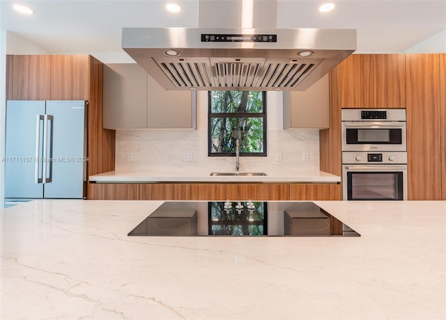 kitchen featuring sink, tasteful backsplash, light stone counters, extractor fan, and appliances with stainless steel finishes