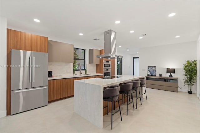 909 NE 16th Ave, Fort Lauderdale, FL 33304 - kitchen with appliances with stainless steel finishes, island exhaust hood, modern cabinets, a breakfast bar, and tasteful backsplash