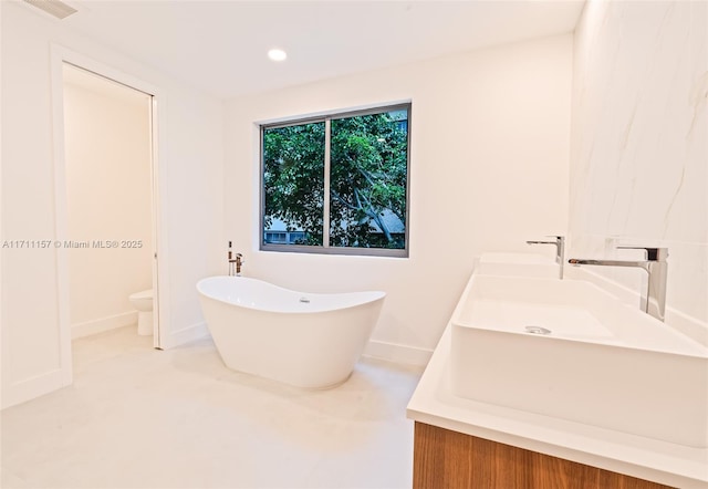 909 NE 16th Ave, Fort Lauderdale, FL 33304 - bathroom featuring a freestanding bath, baseboards, a sink, toilet, and recessed lighting