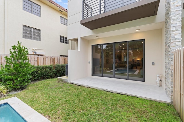 back of house featuring a yard, a balcony, a patio area, and a fenced in pool