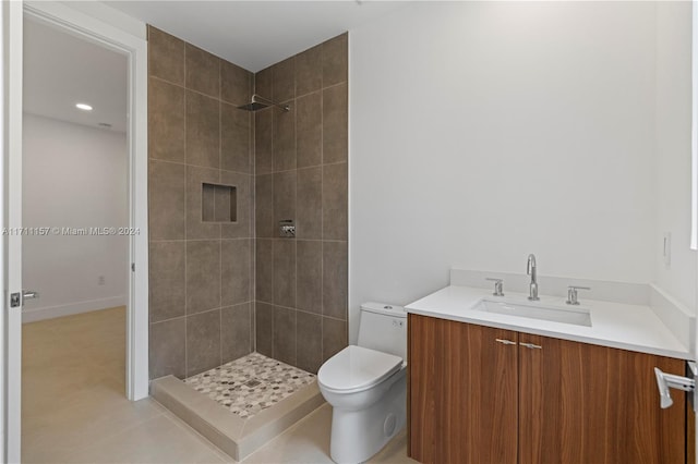 bathroom featuring tile patterned flooring, vanity, toilet, and a tile shower